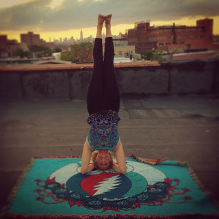 Hippie girl doing a rooftop yoga headstand on a blue Grateful Owl cotton woven blanket